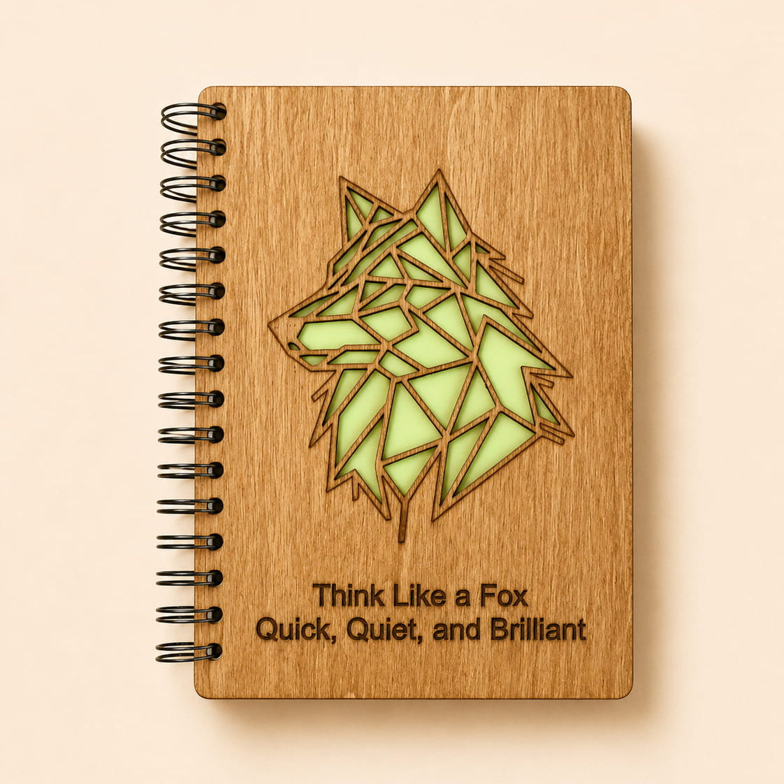 A spiral-bound wooden notebook with a laser-cut geometric fox design and the engraved text 'Think Like a Fox, Quick, Quiet, and Brilliant' on a light beige background.
