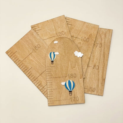 Five wooden arch-shaped growth charts with printed measurement markings and small blue-and-white hot air balloon illustrations, arranged on a light beige background.