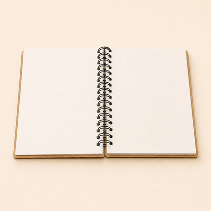 An open blank spiral notebook with white pages and a black metal coil binding, set against a solid light beige background.